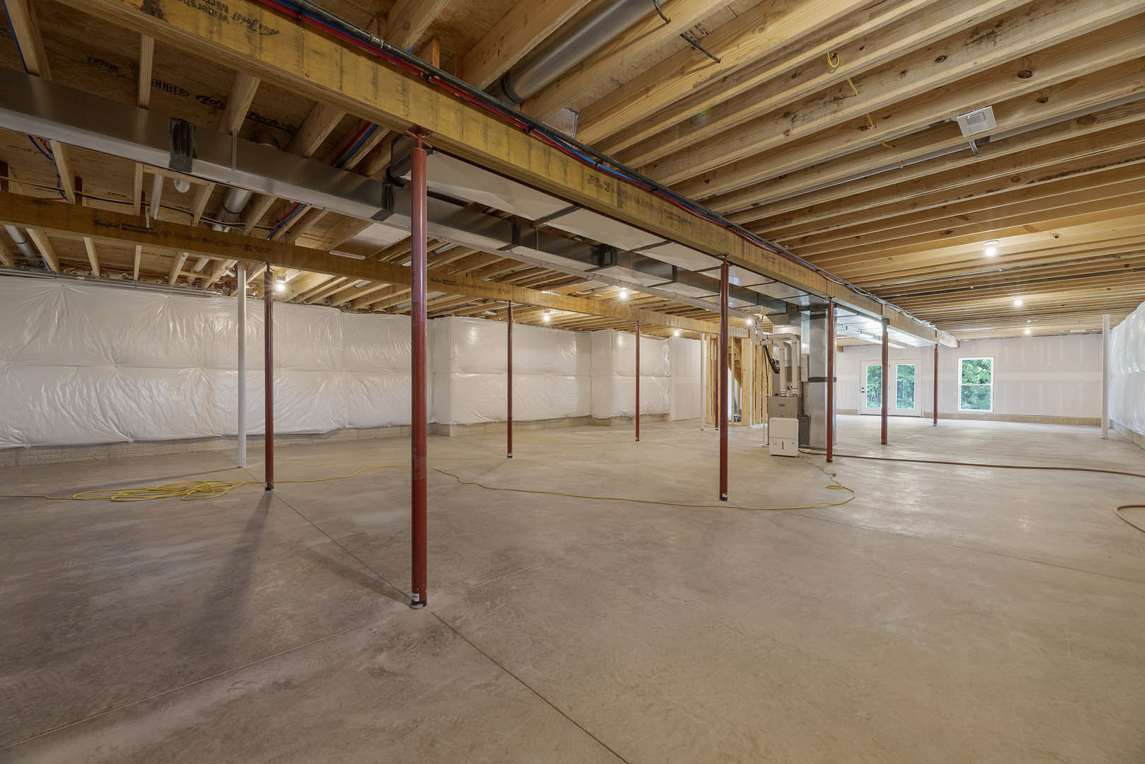 Exposed wooden ceiling beams, concrete floor with red steel poles, window overlooking trees, close-up of light switch on wall
