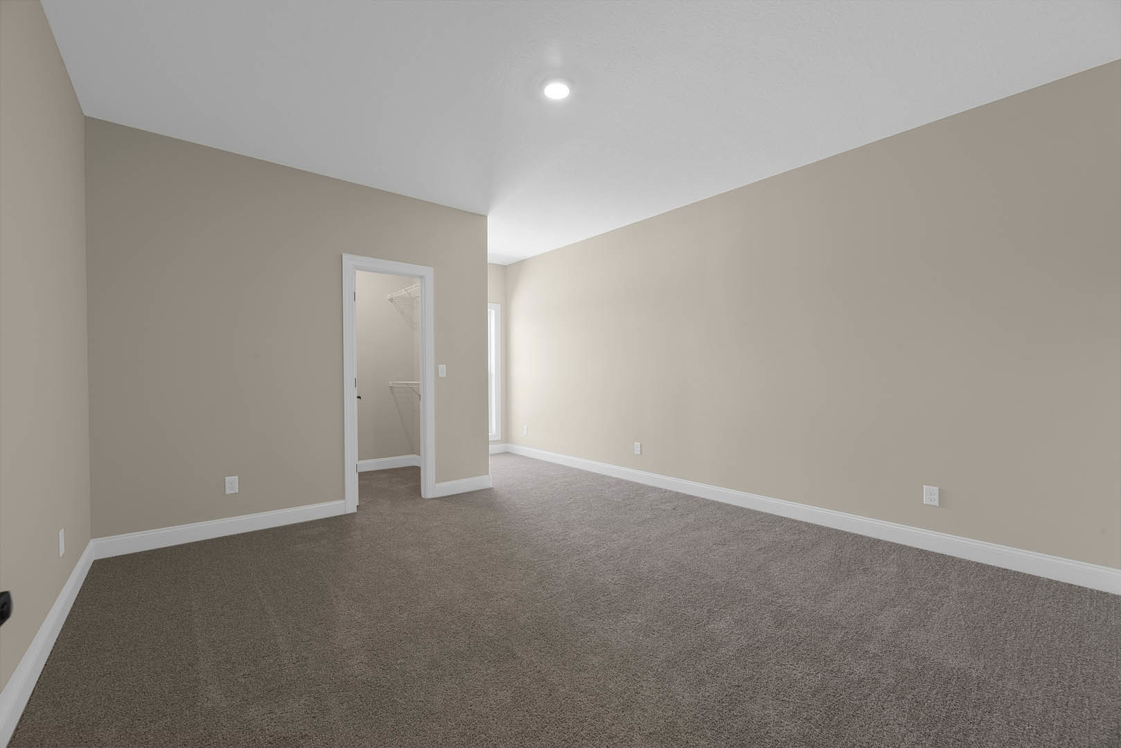 Carpeted room with white trim, open white-framed door, ceiling light fixture, and white wall shelf