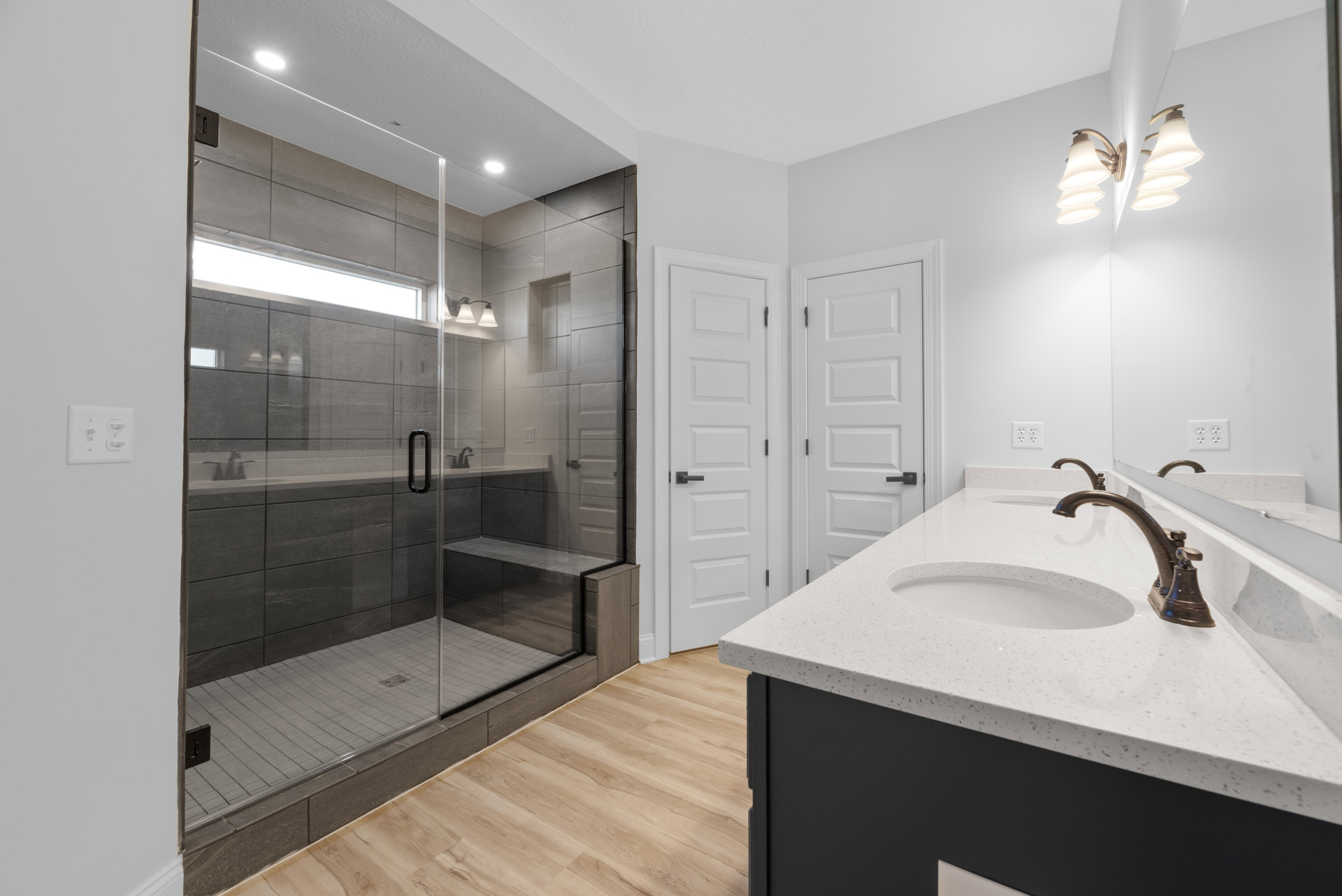 Bathroom with glass shower enclosure featuring built-in bench and window, modern sink with chrome faucet, tiled walls, and contemporary lighting fixture