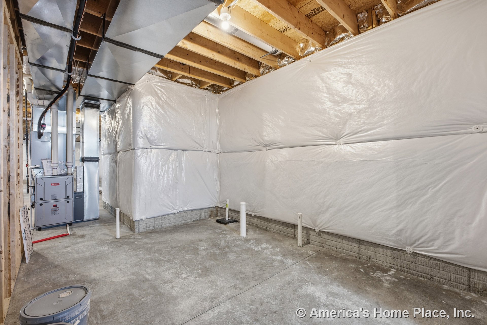 Unfinished basement with exposed ceiling joists, ductwork, insulated walls, concrete slab floor, visible plumbing rough-ins, utility furnace, unfinished wood framing, and overhead
