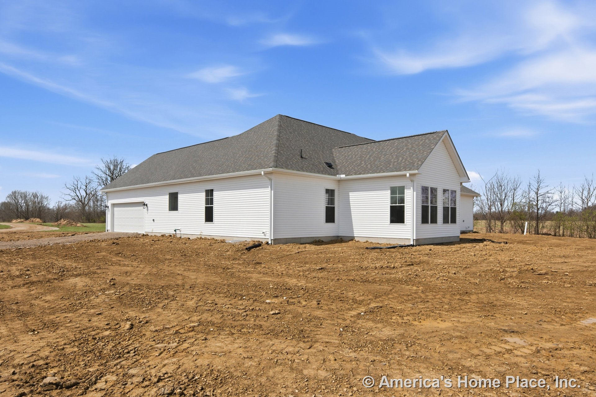White vinyl siding single-story home with dark asphalt shingle gable roof, attached two-car garage, multiple double-hung windows, exterior trim, outdoor lighting fixture, and