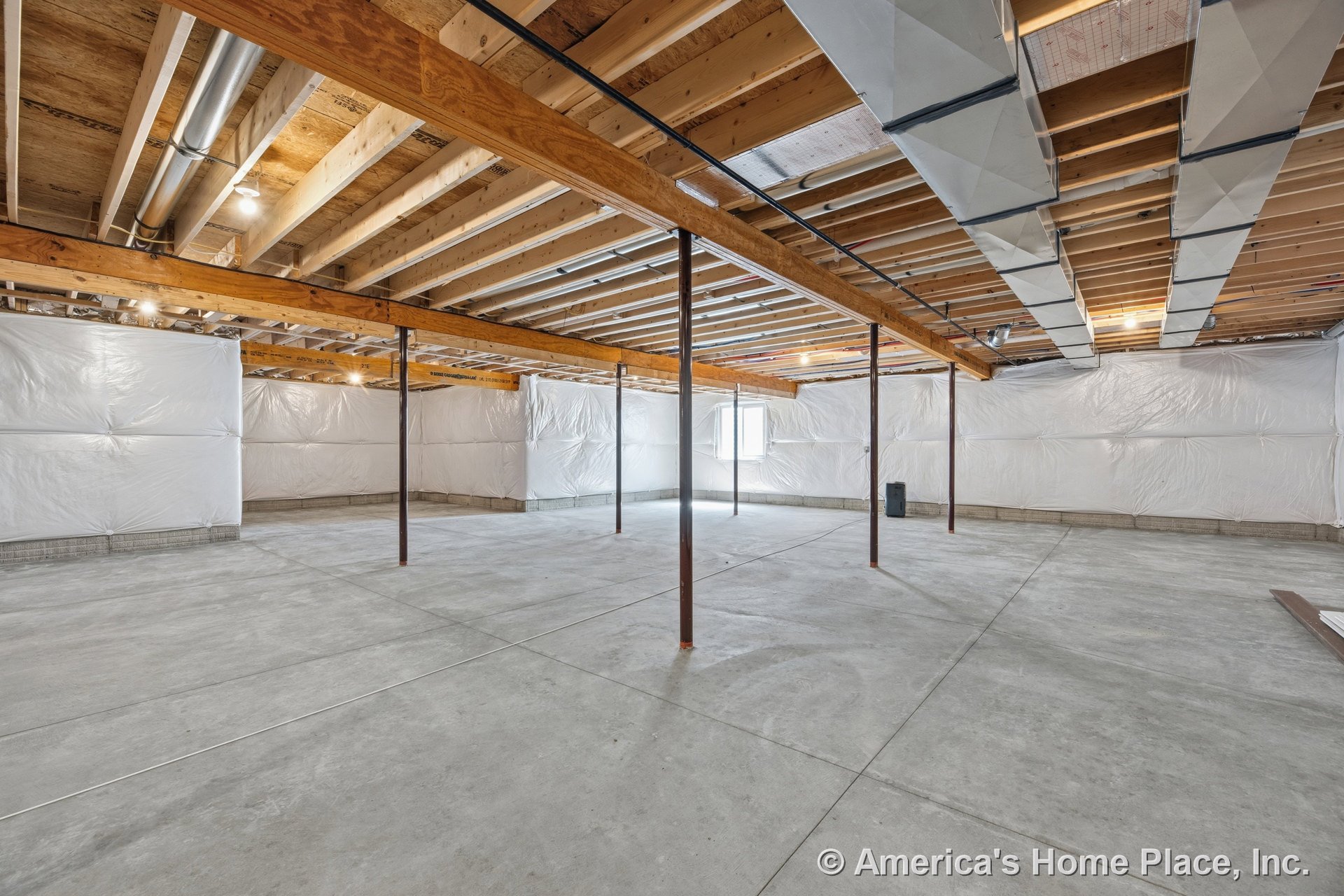 Unfinished basement with exposed wood ceiling beams, visible metal ductwork, concrete slab floor, insulated plastic-wrapped walls, metal support columns, single window, and utility