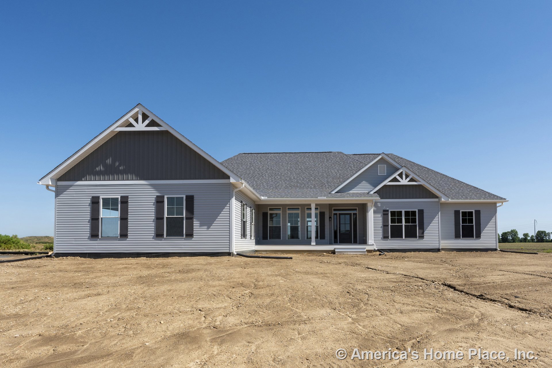 Gray vinyl siding exterior with gable rooflines featuring asphalt shingles, covered front porch supported by white columns, white trim accents, multiple double-hung windows with