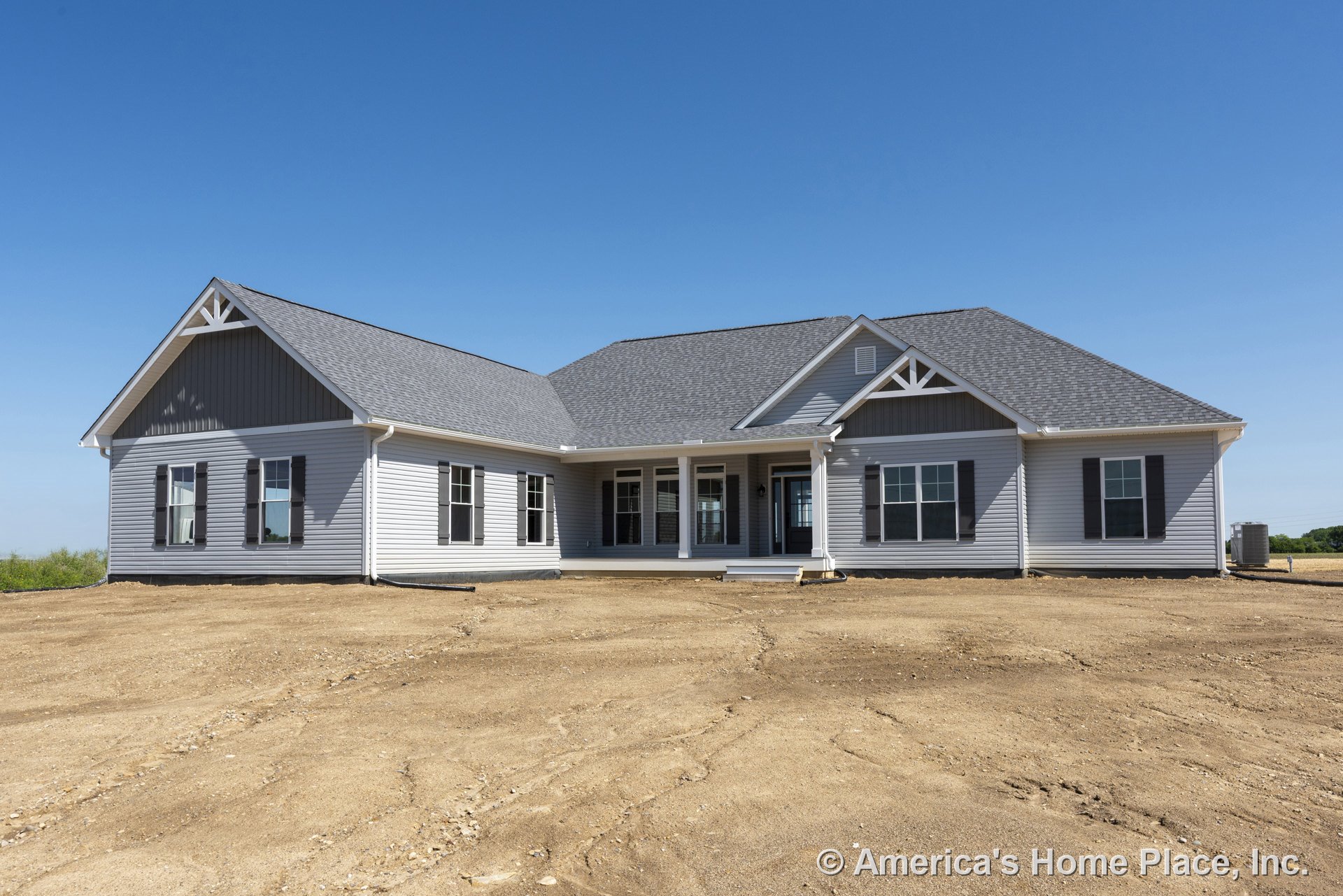 Single-story home with gray vinyl siding, architectural roof shingles, covered front porch, multiple double-hung windows, decorative gable trim, and black window shutters.