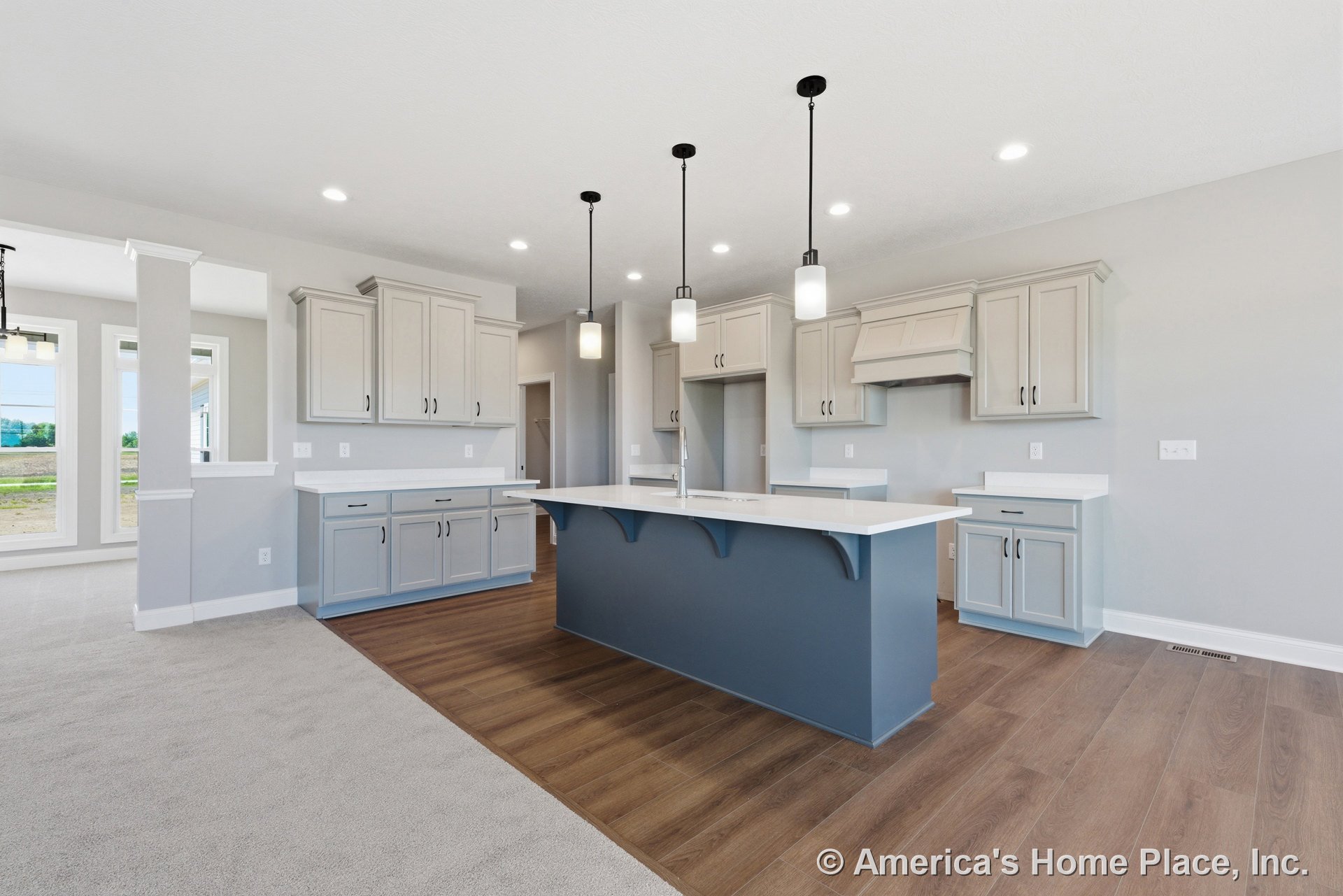 Open kitchen with light gray upper cabinets, blue island featuring built-in sink and white quartz countertops, wood-look flooring, pendant and recessed ceiling lighting, stainless