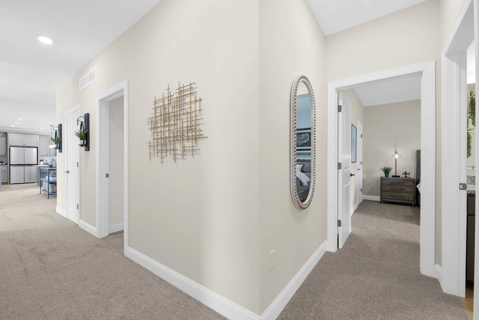 Hallway with light wood flooring, wall-mounted mirror, bird artwork, stick wall art, white refrigerator with black trim, dresser topped with lamp, bright ceiling light