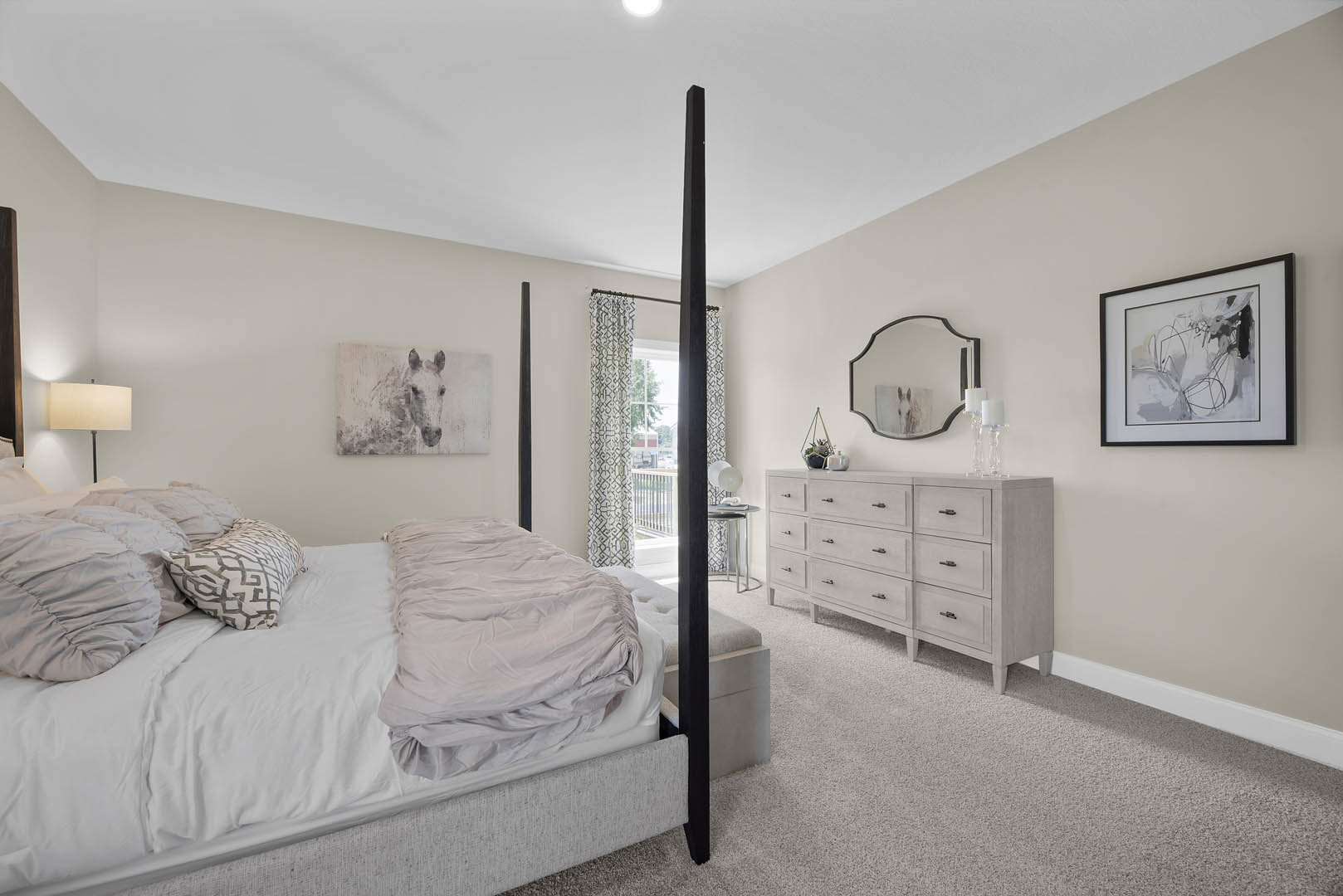 Bedroom with a white dresser, bed layered with pillows and blankets, wall-mounted framed picture, and a mirror reflecting a horse image.