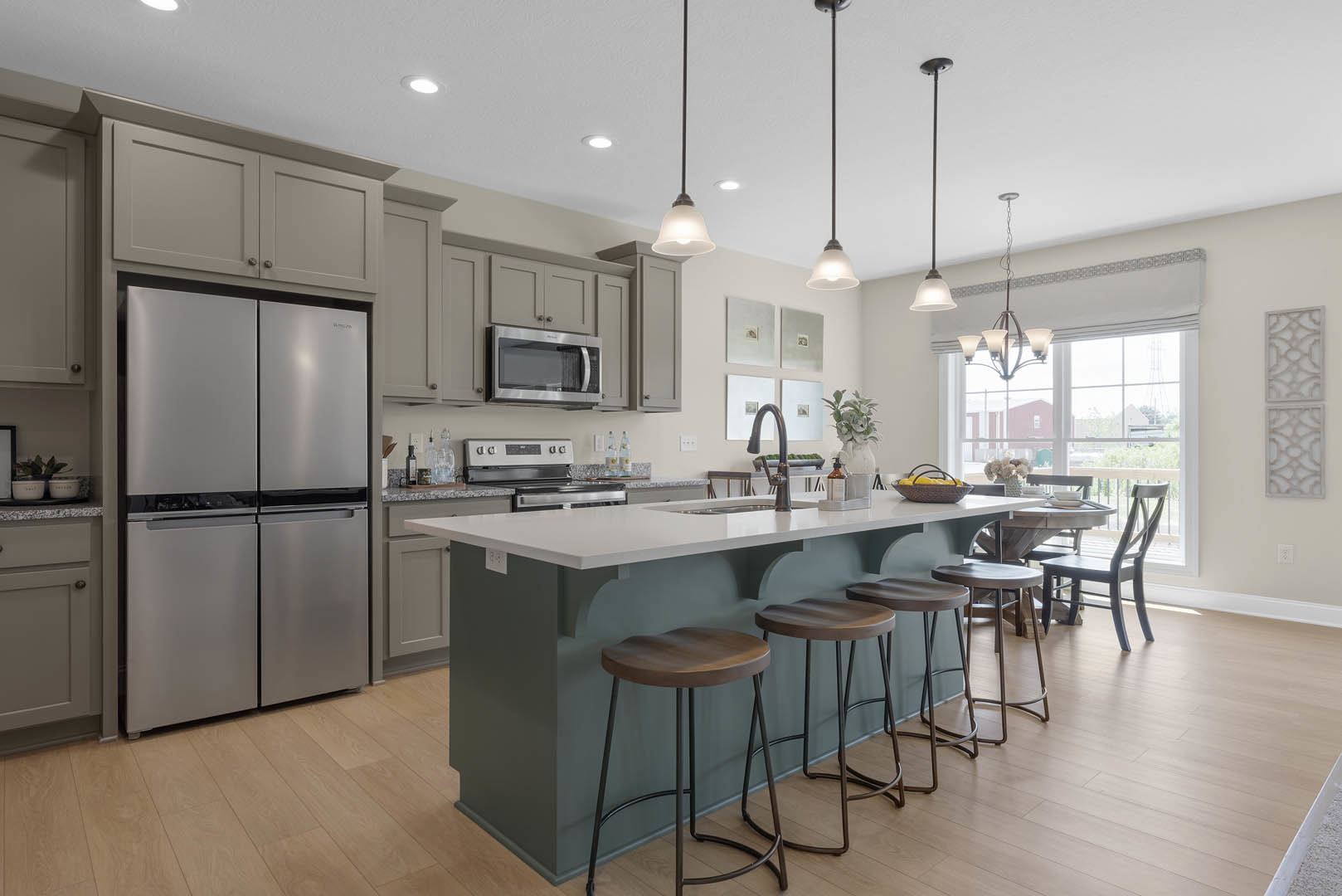 Modern kitchen featuring a bar with upholstered stools, stainless steel refrigerator, built-in microwave, white cabinetry, quartz countertops, and wood flooring