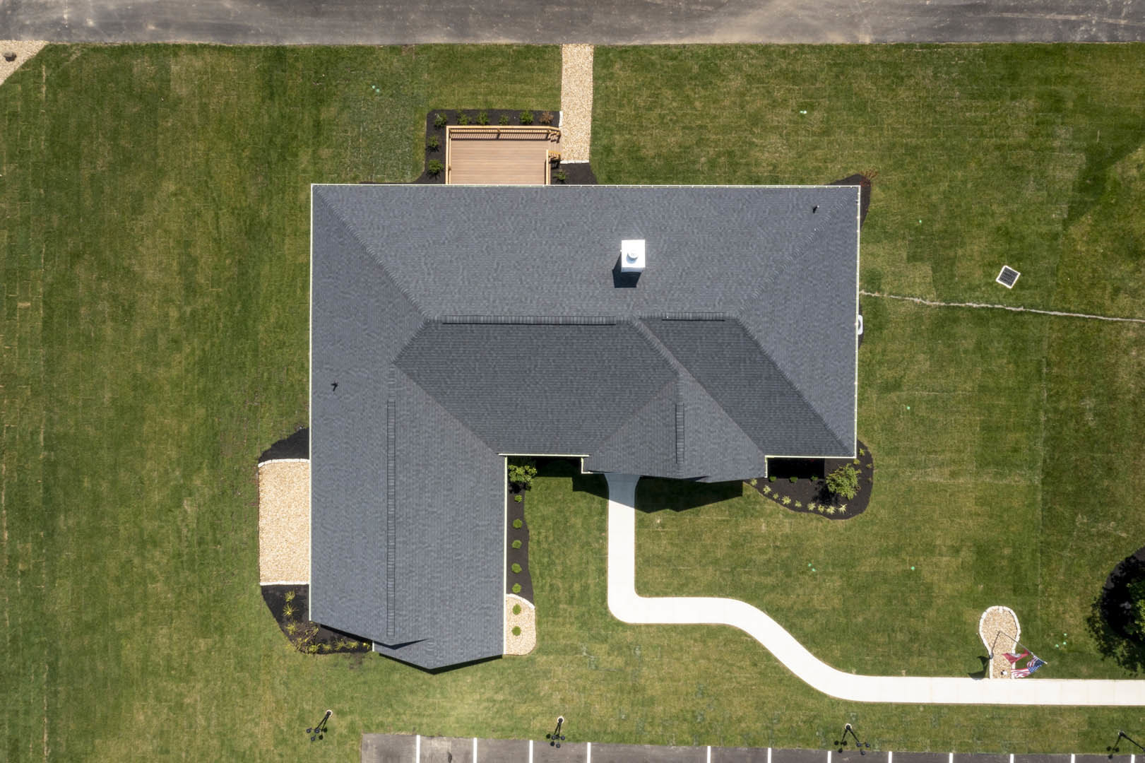 Two-story home with white siding, manicured lawn, paved parking area, and concrete walkway leading to the entrance