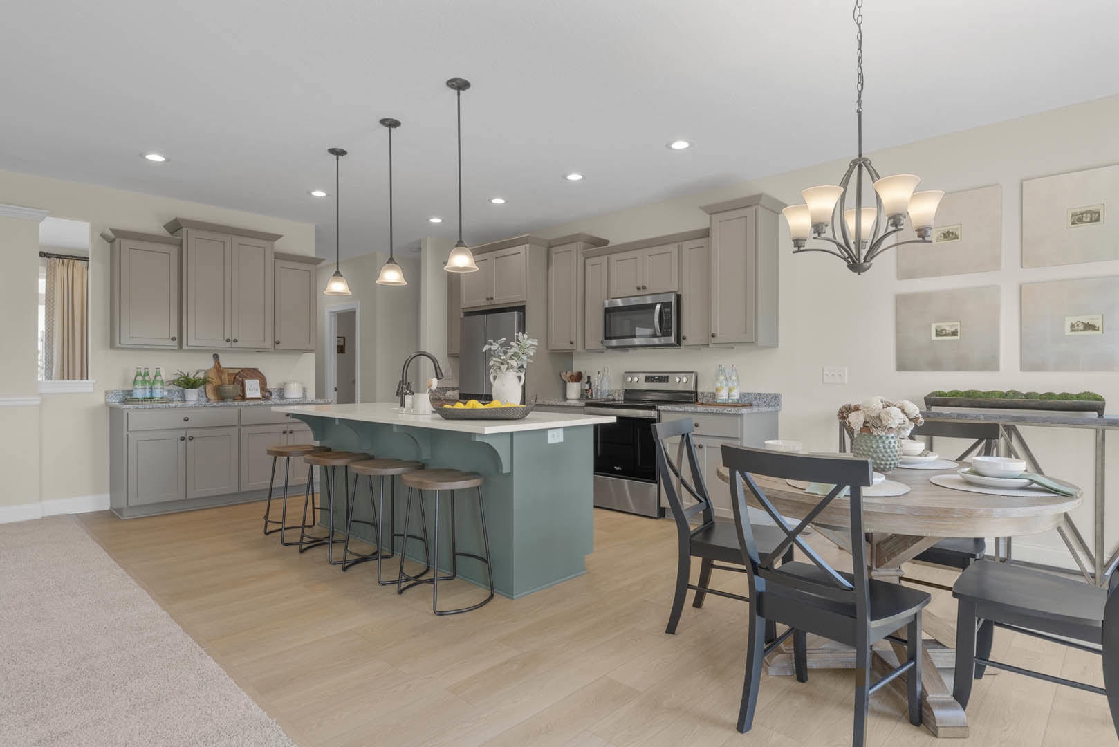 Open kitchen and dining area featuring wood cabinetry, stone countertops, dining table with upholstered chairs, bar stools at island, microwave built into cabinets, white vase with