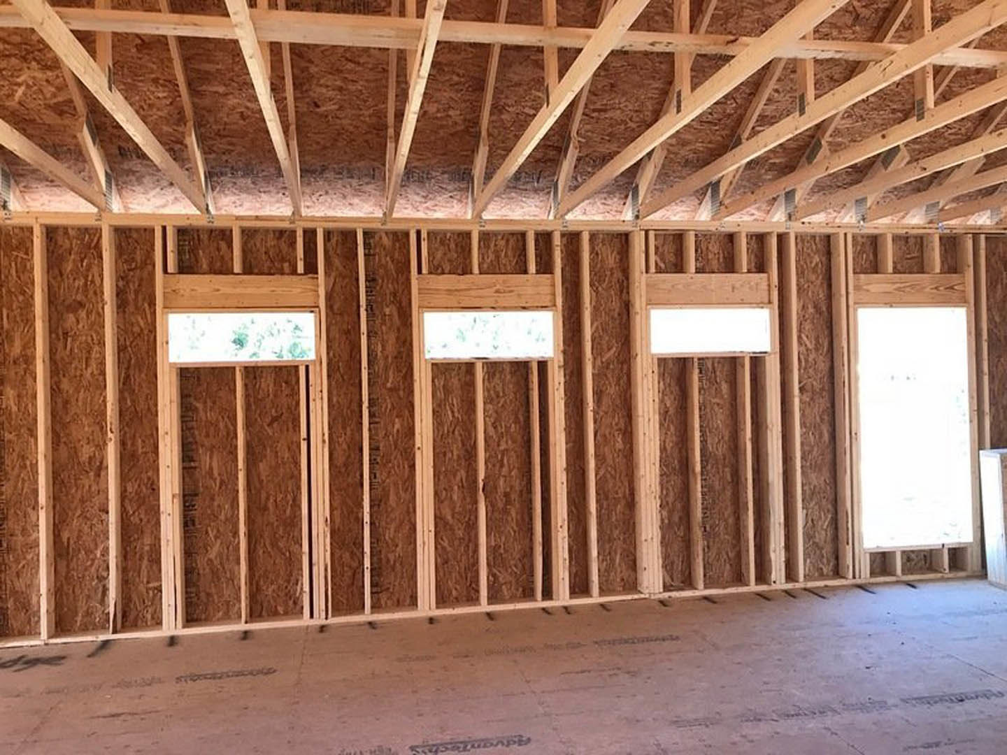 Open-concept room with exposed wooden ceiling beams, white walls, and large rectangular windows letting in natural light