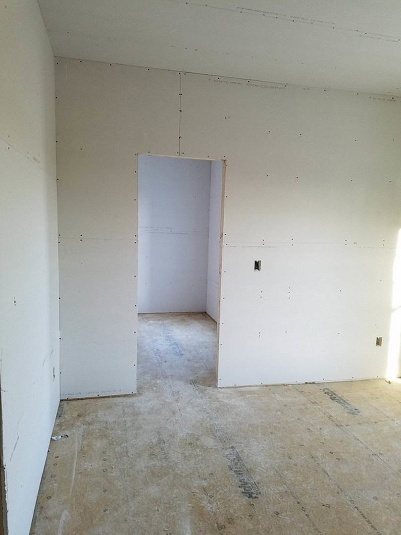 White plaster wall with wooden door frame, open door, concrete floor with black line, stone surface detail