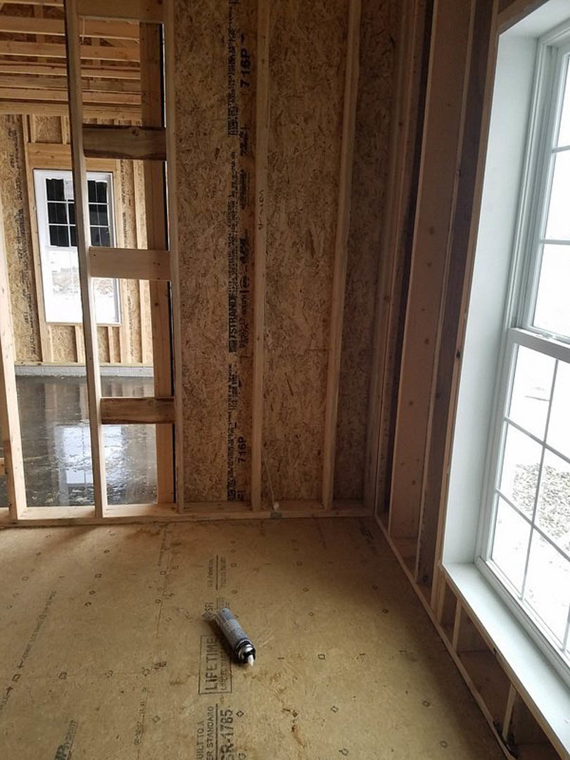 Sunlit room with plaster walls, wooden cross-braced window, and spray paint can on light wood flooring