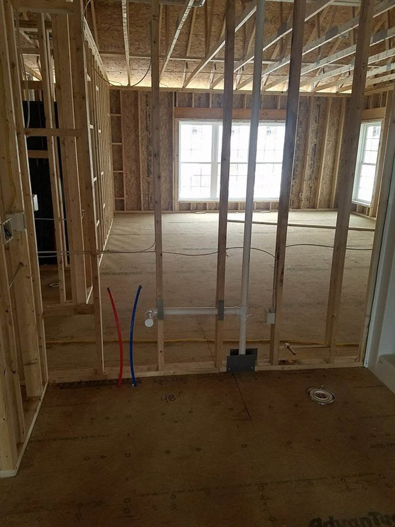 Open doorway and large window in a room with exposed wood beams, plank flooring, and composite wall insulation.