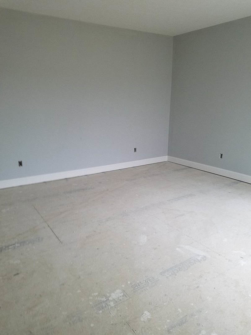 Gray walls with crisp white trim, white baseboards, and smooth concrete flooring in a modern interior room