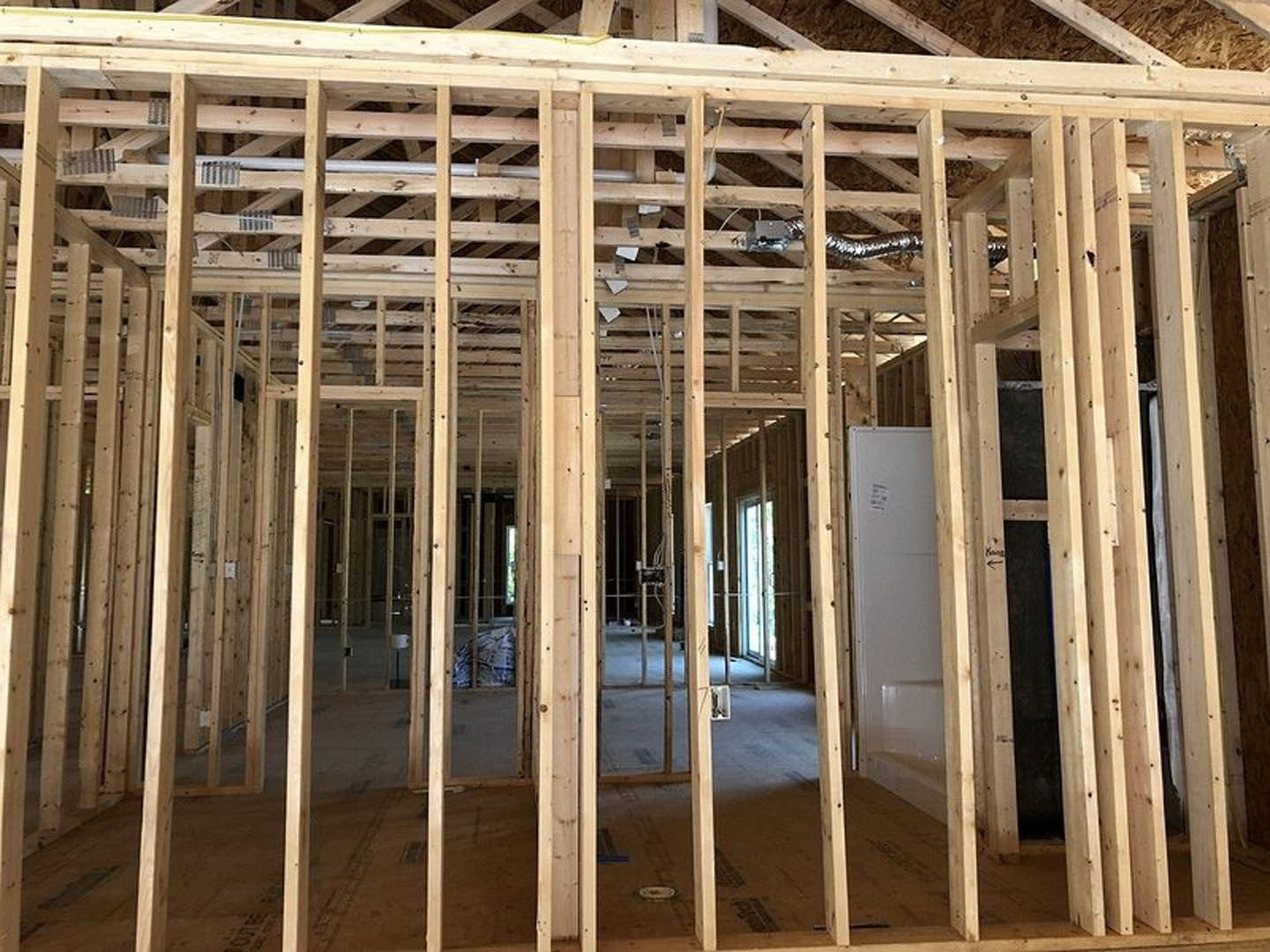 Exposed wooden framing and beams surrounding a window opening in an unfinished interior wall