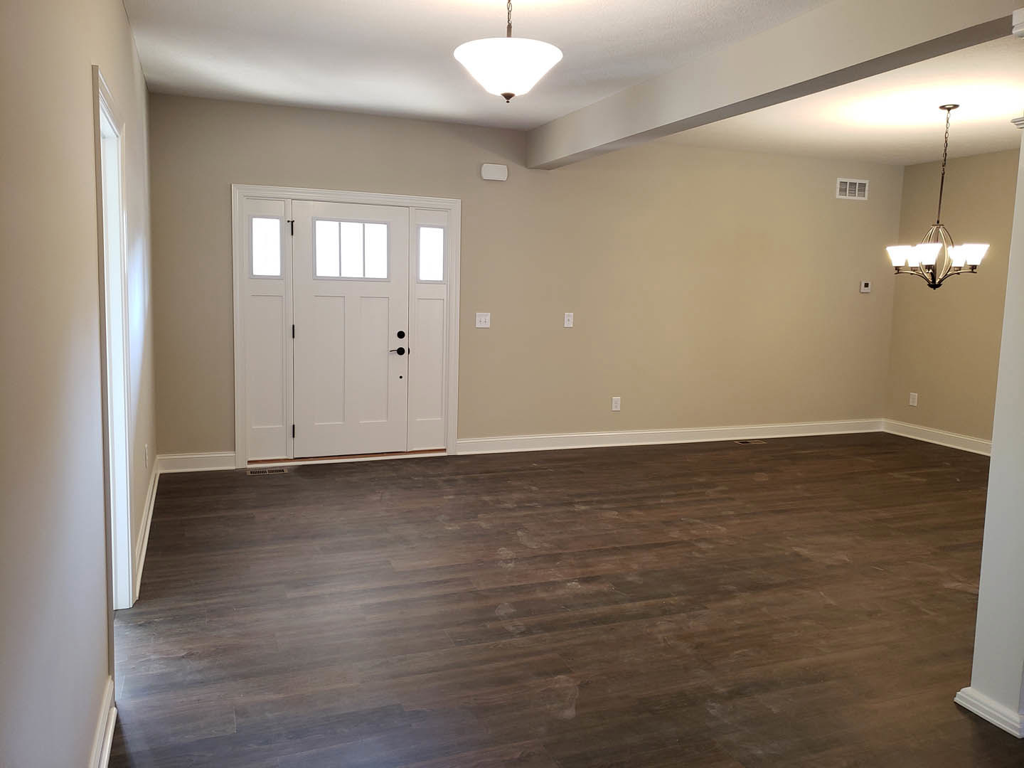 Hardwood floor with white baseboards, white door featuring three glass panes, chandelier hanging from ceiling, window with white trim