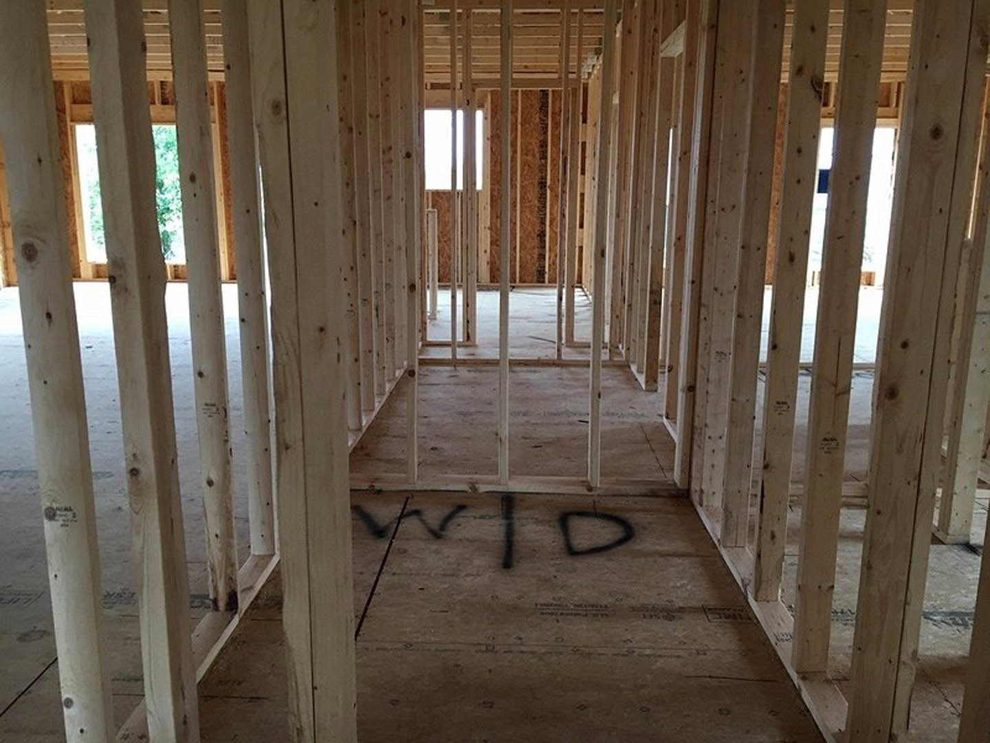 Wood-framed room with exposed beams, unfinished plank flooring, and a large window providing daylight