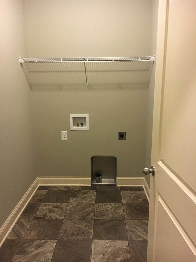 Small closet with tile floor, metal shelving, a metal container on a shelf, white framed access panel with red and blue water sprinkler, and close-up of a door knob.