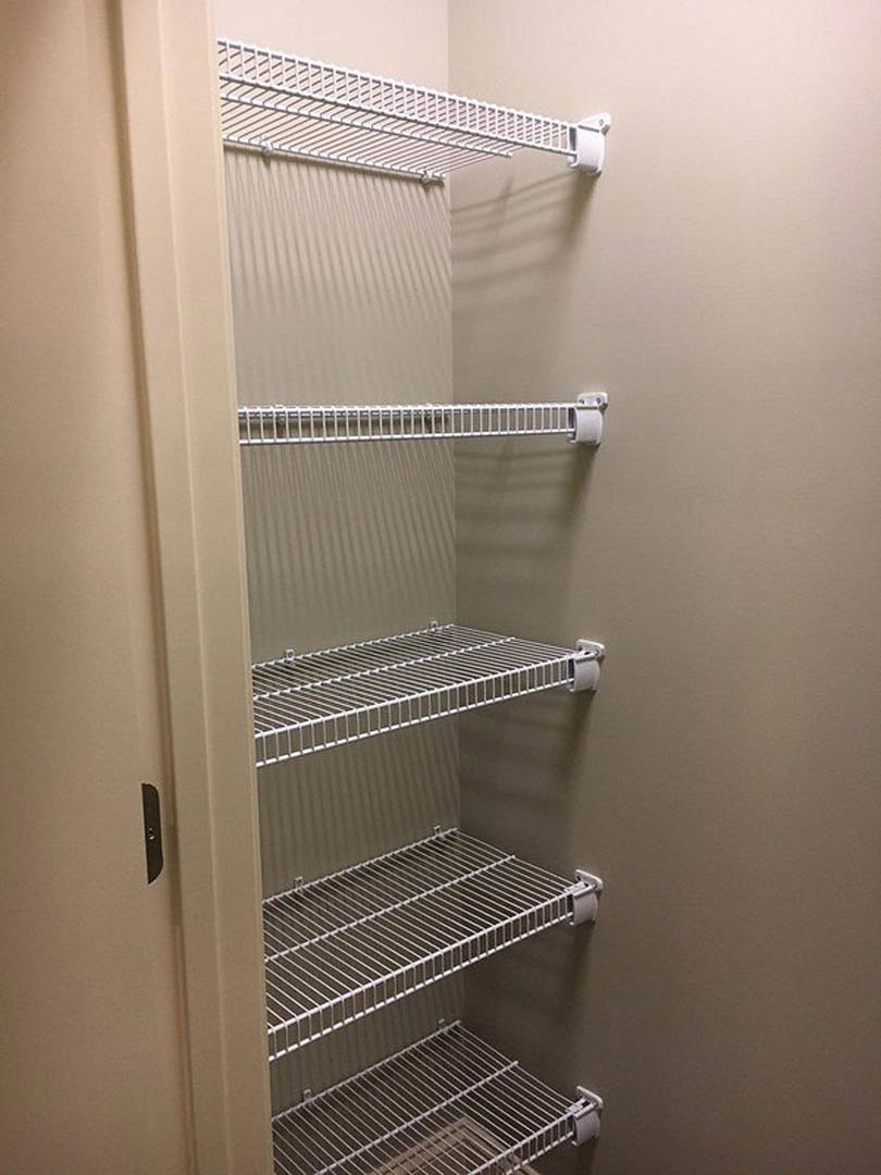 Walk-in closet with white wire shelving and a white metal ladder mounted on the wall
