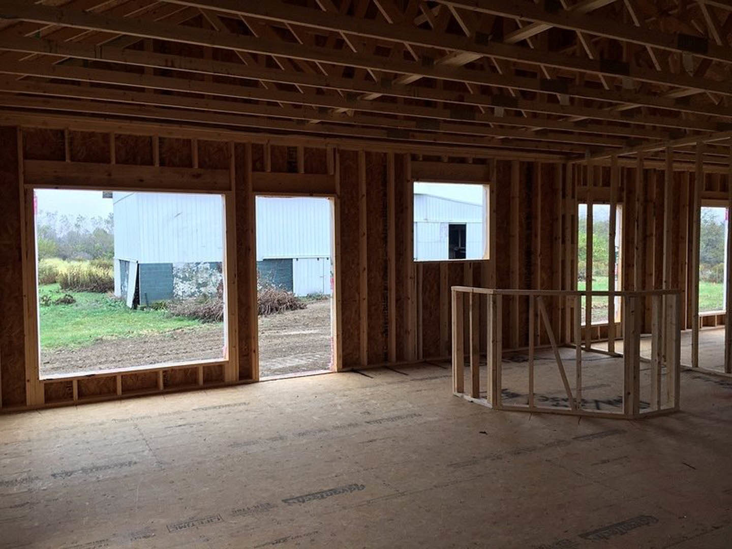 Spacious room featuring large windows framed in wood, wide plank hardwood flooring, and views overlooking an open grassy field