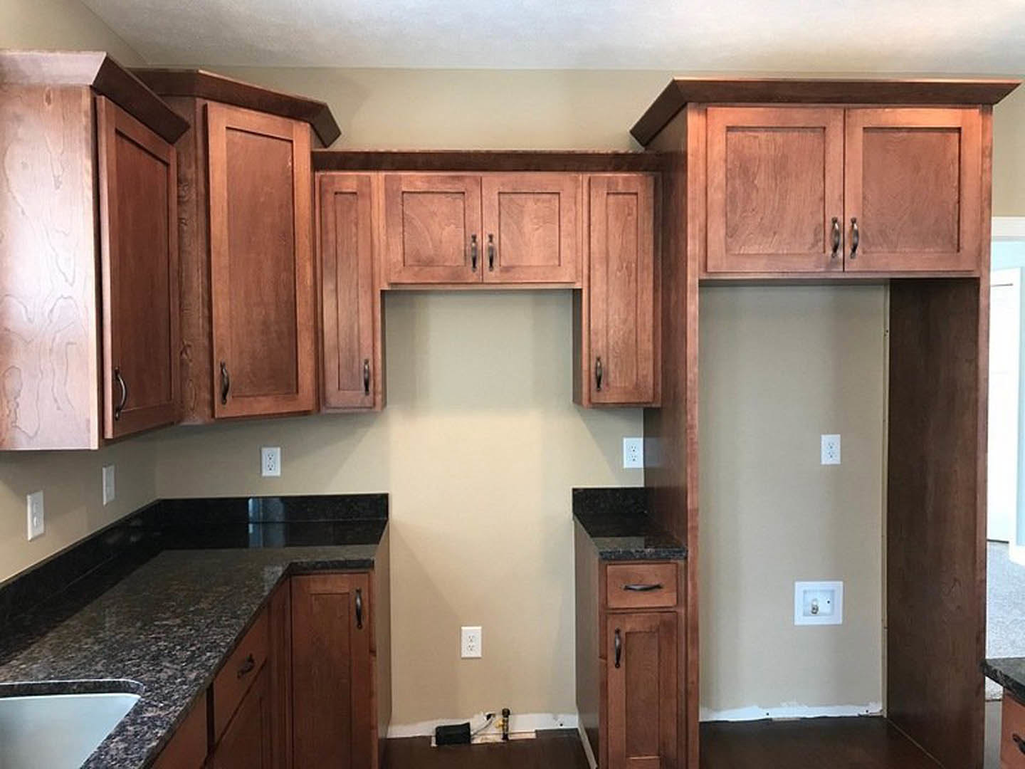 Kitchen featuring dark wood cabinets, black granite countertops, stainless steel sink, and white walls