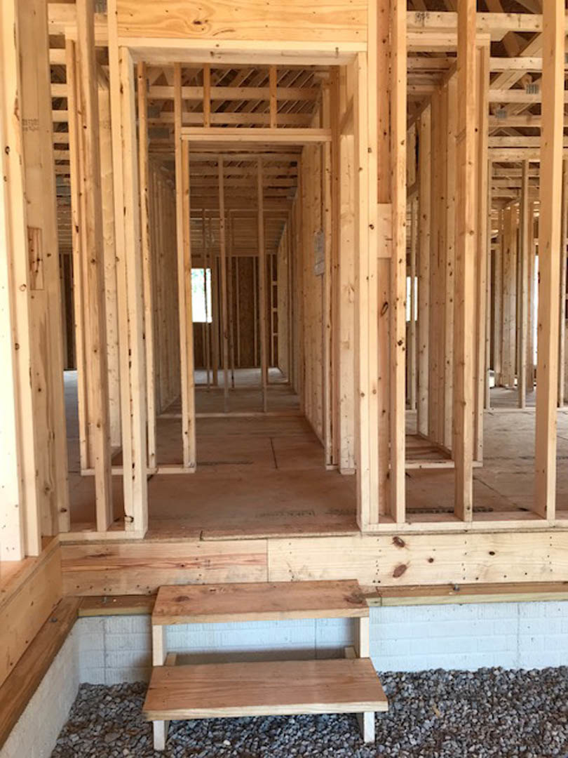 Exposed wooden framing and beams inside a partially constructed home with visible lumber and insulation materials