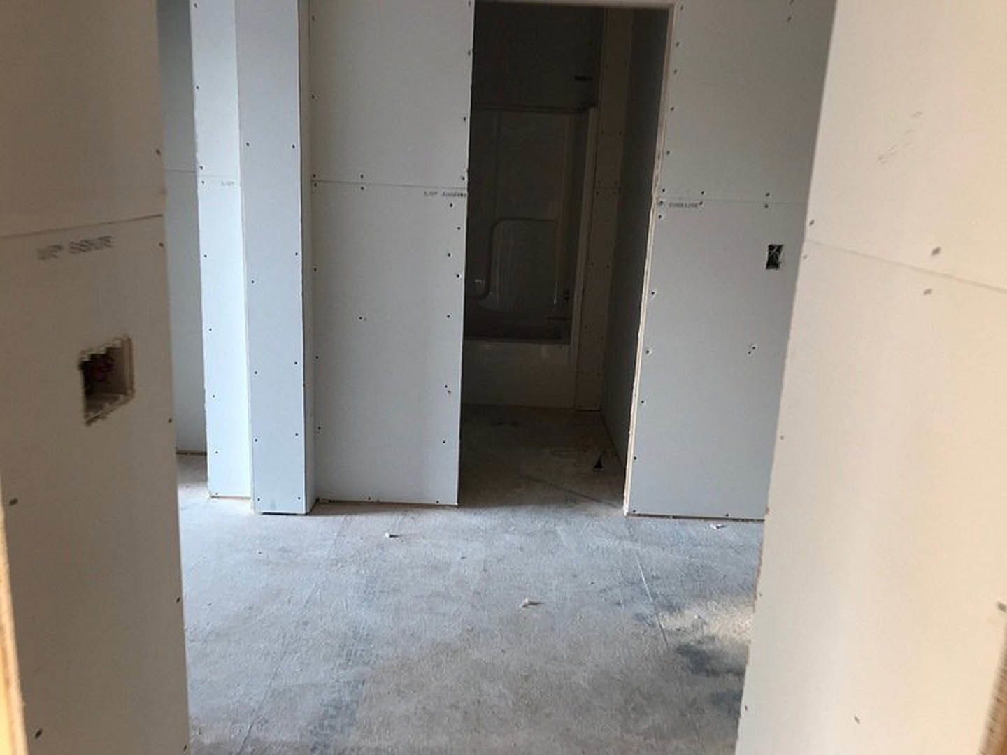 White walls, concrete floor, and a simple door with black text on the surface in a minimalist interior room