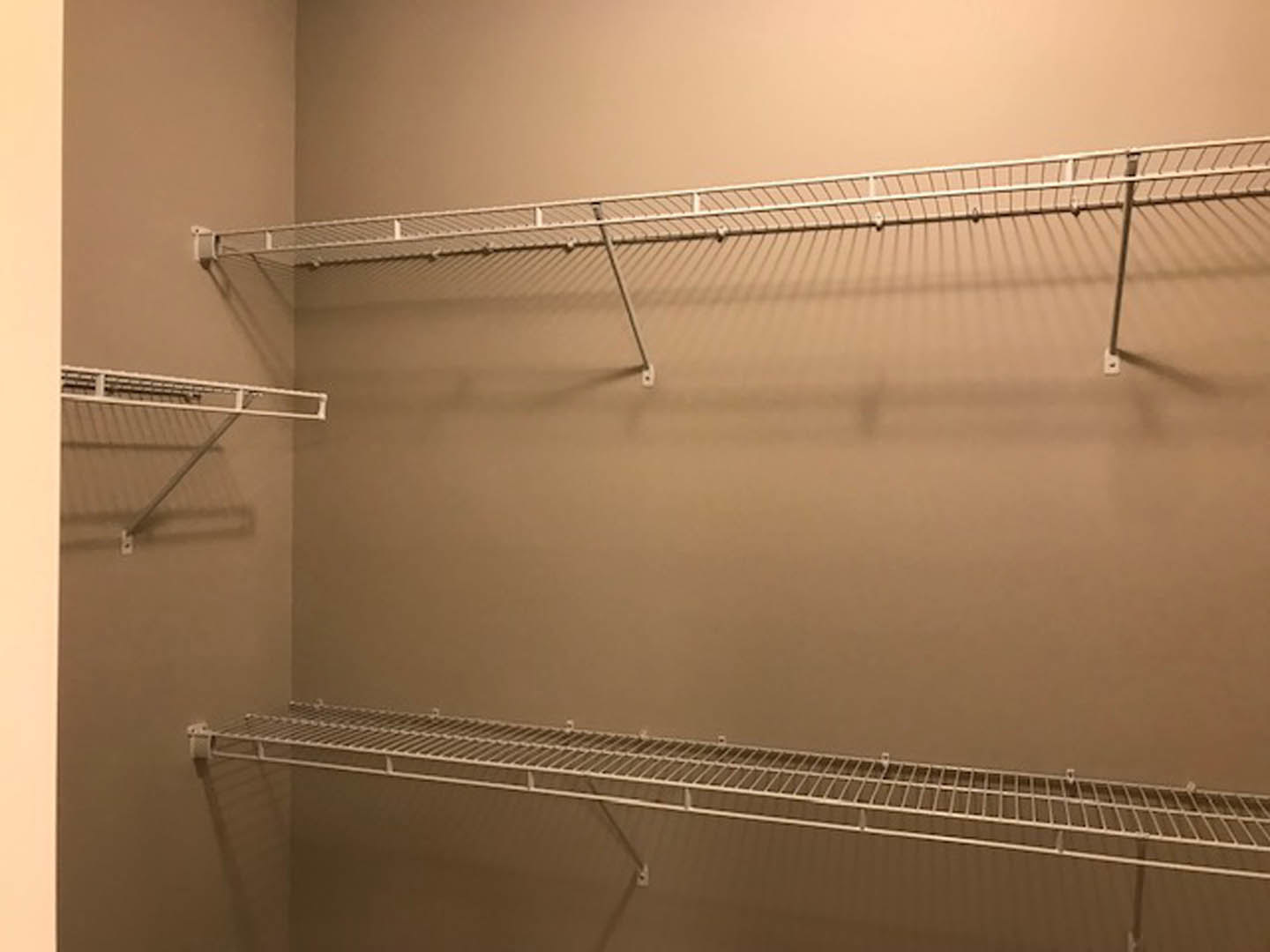 White closet with built-in metal rod and open shelving against smooth painted walls