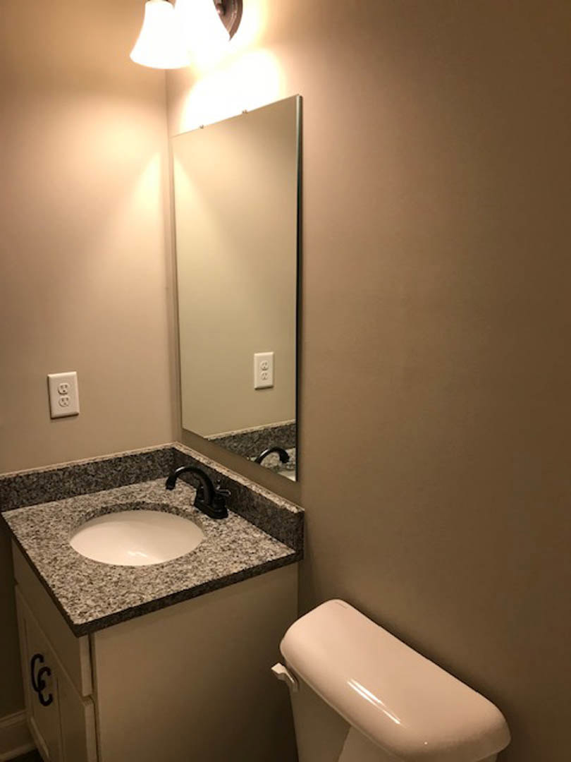 Modern bathroom featuring a white porcelain sink with a matte black faucet, adjacent to a white toilet, light gray tile walls, and chrome plumbing fixtures.