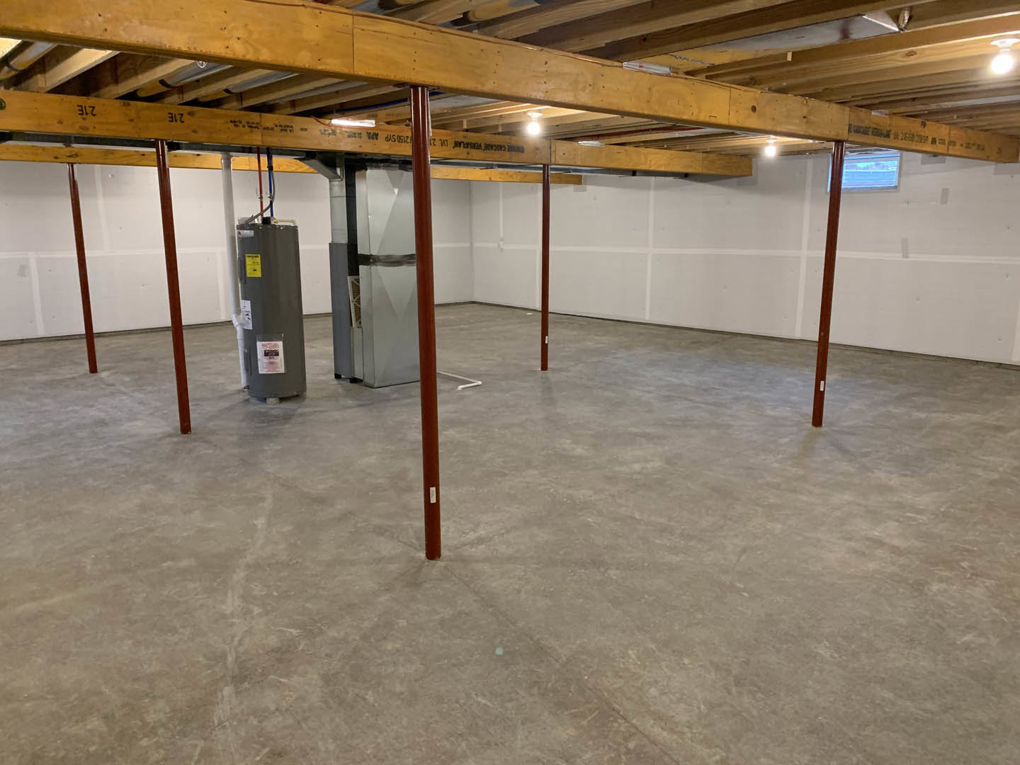 Concrete floor with exposed metal pole, wooden ceiling beam, and neutral walls in a residential interior room