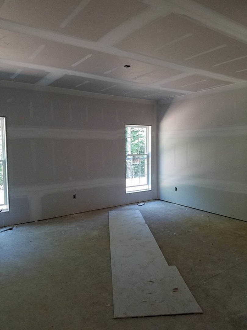 Bright room with smooth white plaster walls, large window with white frame, pale wood plank flooring, and ceiling featuring recessed lighting fixture.