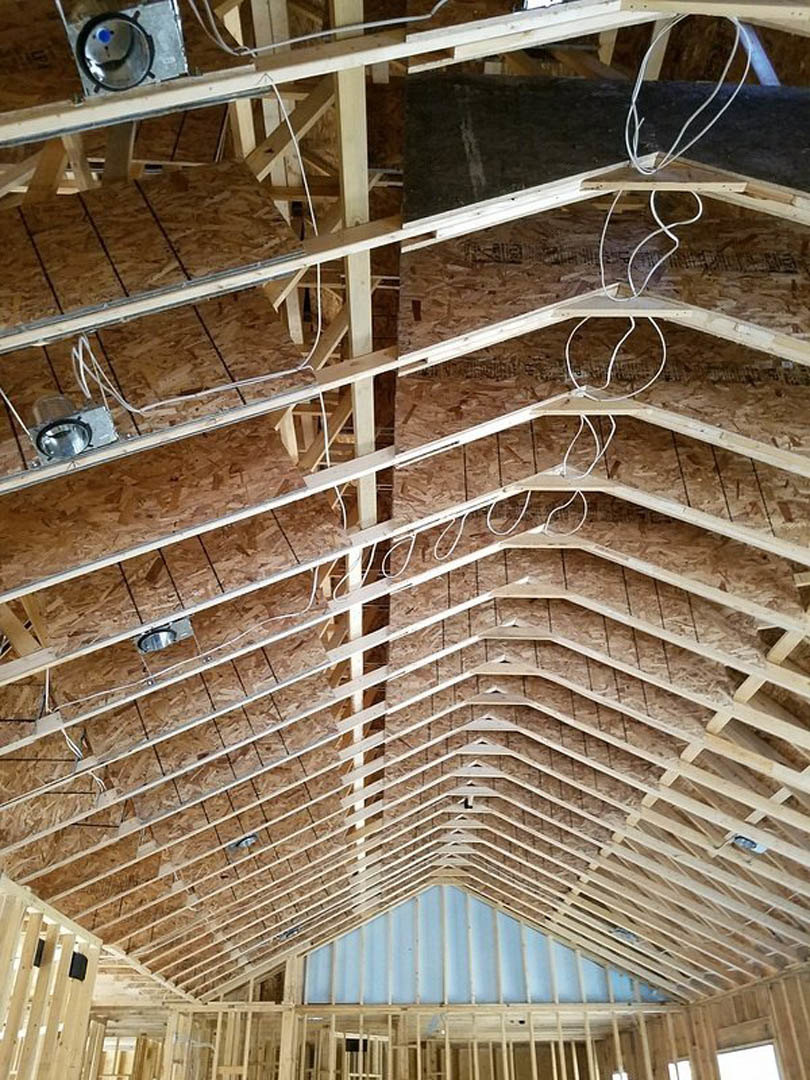 Exposed steel beams and composite ceiling panels with daylight filtering through, highlighting modern indoor finishes