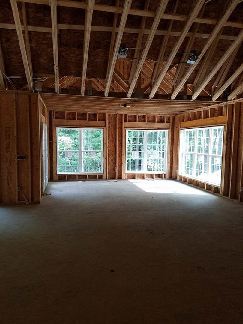 Wood plank ceiling with exposed beams, multiple windows with white and wood frames, natural daylighting, neutral walls, residential interior.