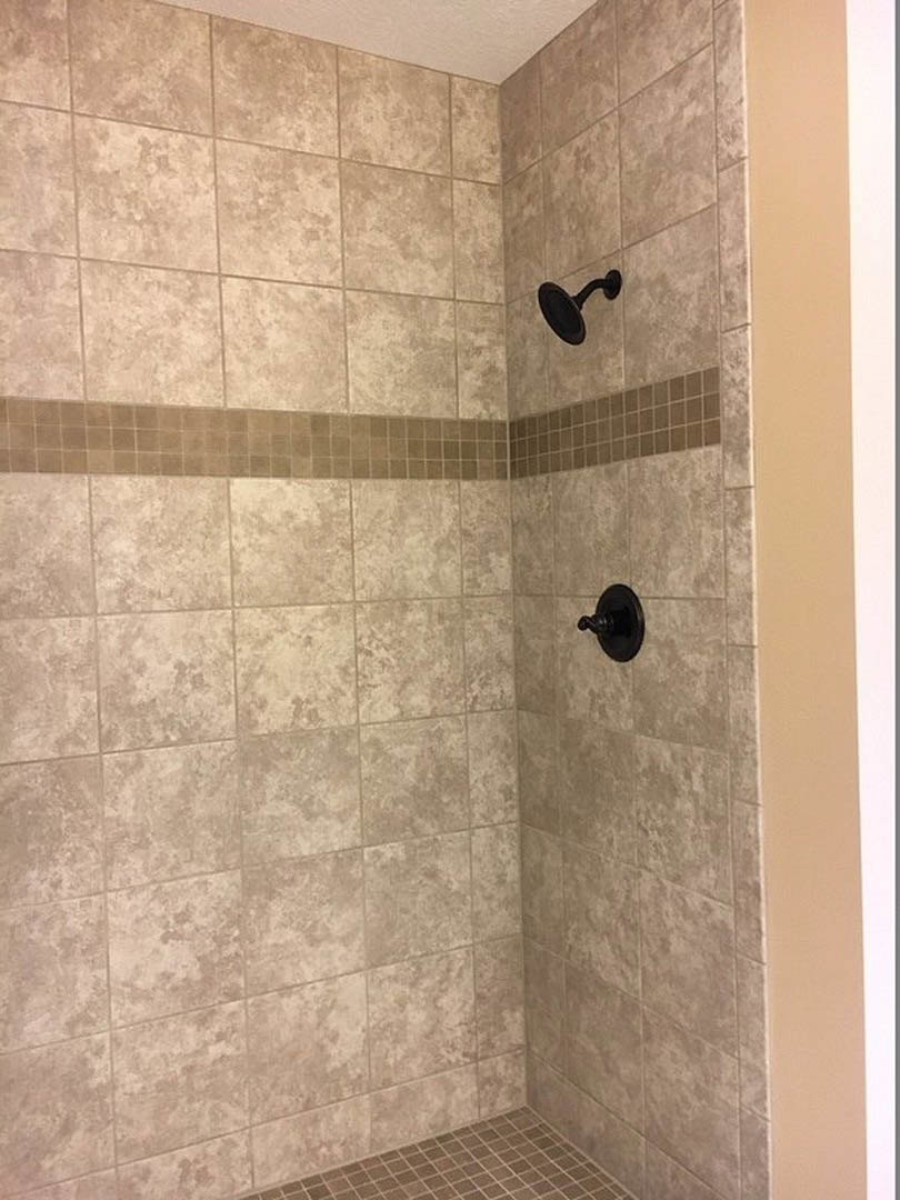 Walk-in shower with white subway tile walls, chrome showerhead, and light gray tile flooring