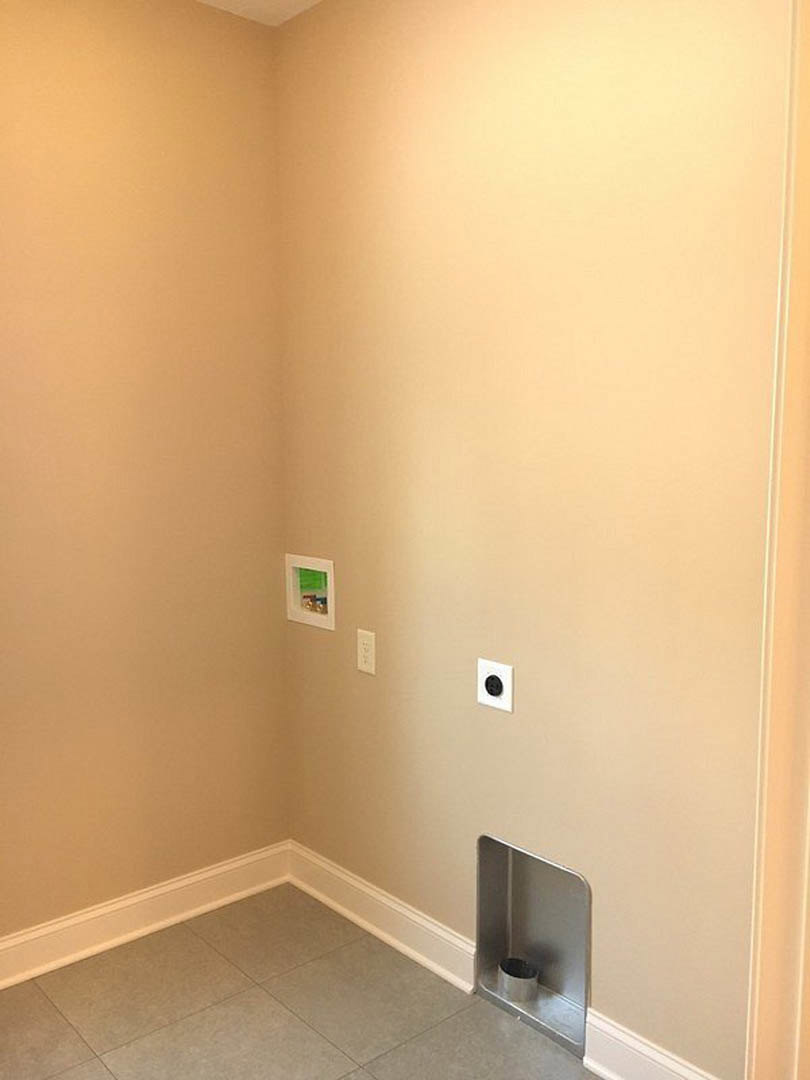 Plaster bathroom wall with a hole, black electrical outlet, tile flooring, metal trash can in corner, white rectangular device with green screen