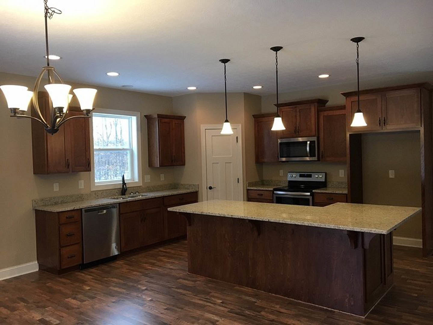 Spacious kitchen featuring a large central island with quartz countertop, stainless steel dishwasher, modern cabinetry, built-in microwave, gas stove, silver refrigerator, and a