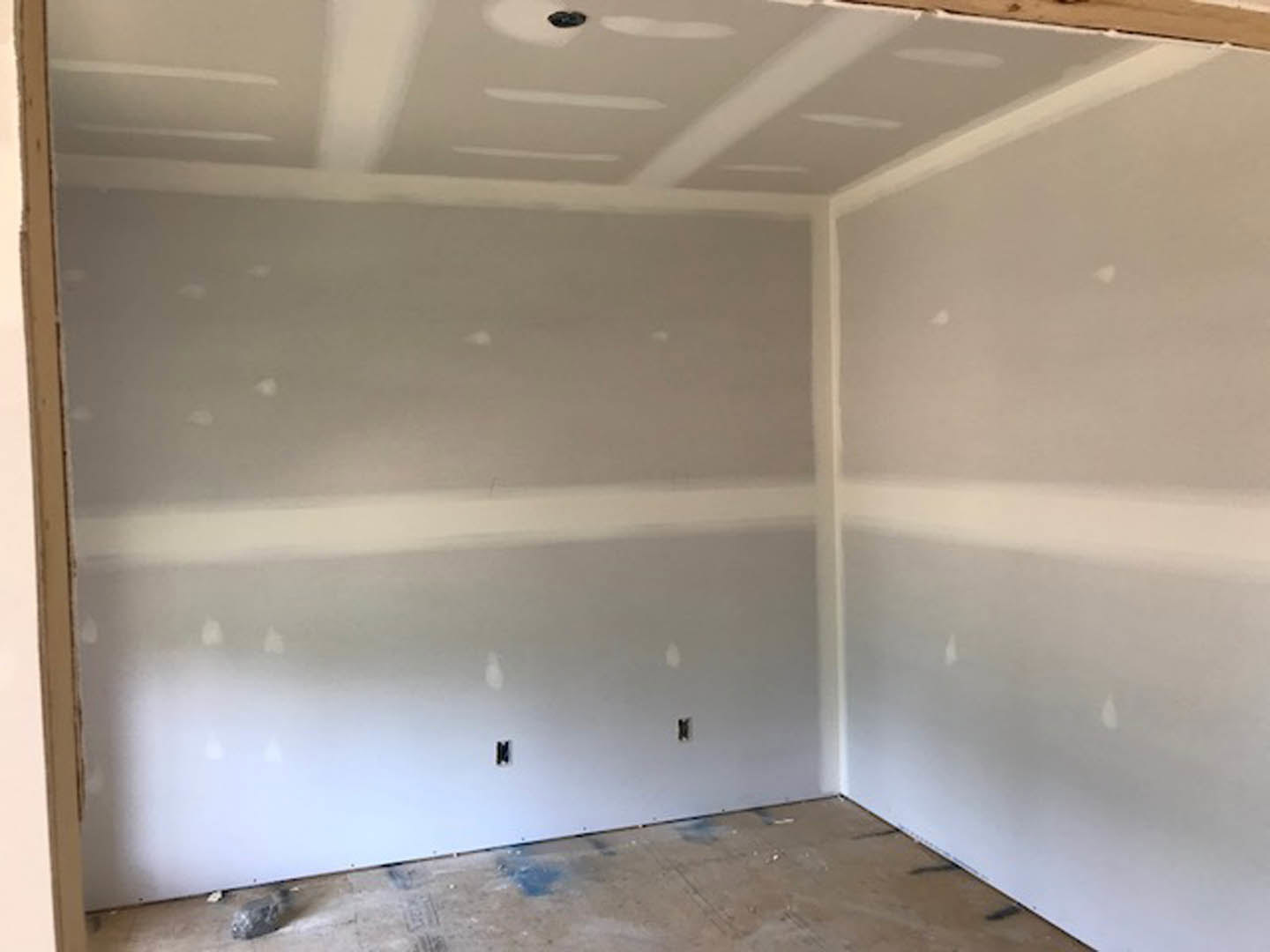 White-walled room with white plaster ceiling, light-colored floor, and a white wall featuring subtle vertical stripes; close-up views of a table surface and a textured rock are
