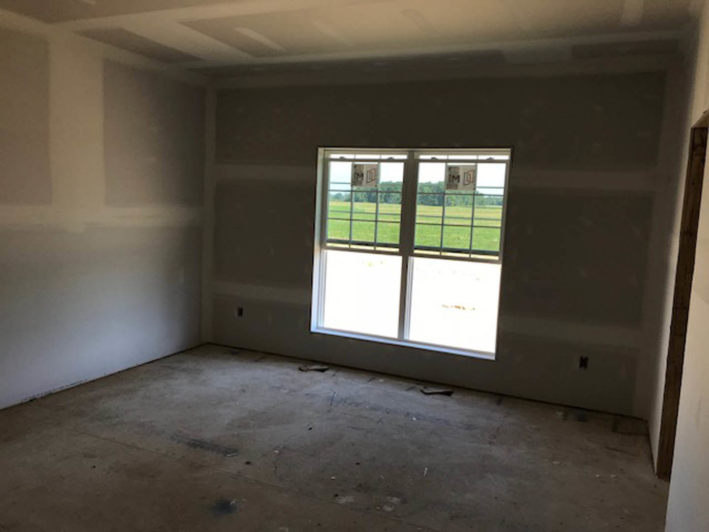 Sunlit room with large window, smooth concrete floor, white plaster walls, and minimal furnishings