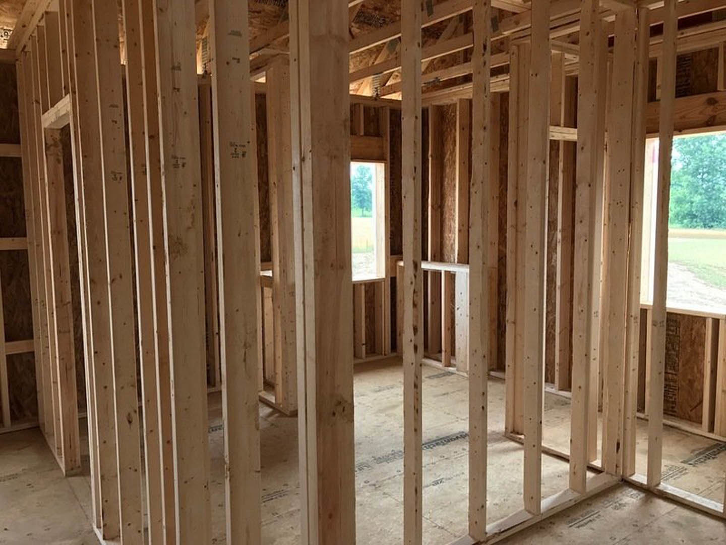 Exposed wood framing and beams inside unfinished room with visible lumber and subfloor