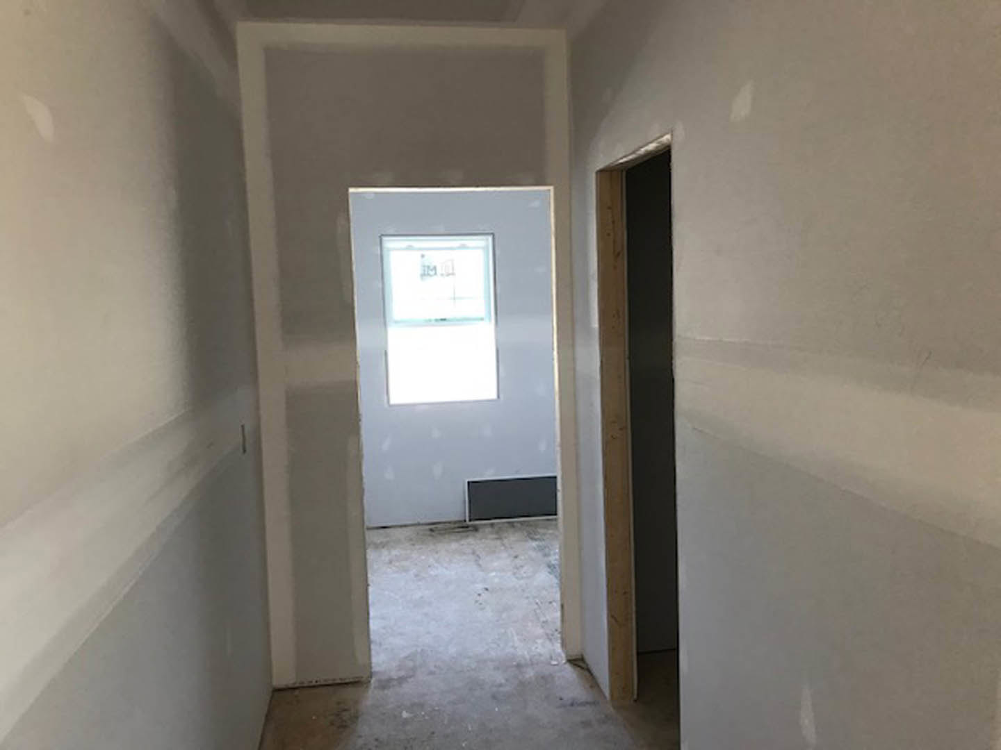 Hallway with white plaster walls, light wood flooring, a wooden door, and a window featuring a decorative drawing