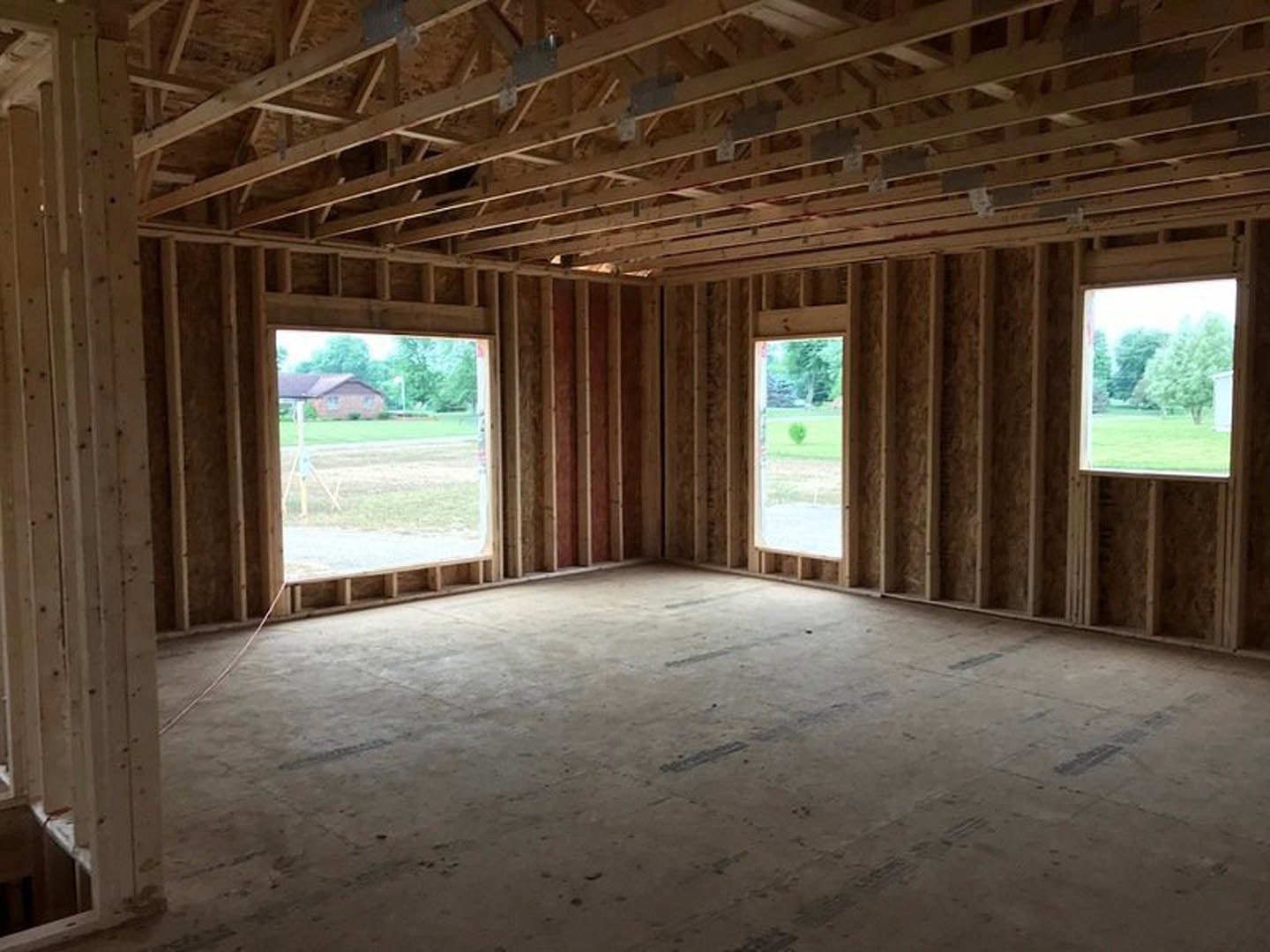 Spacious room featuring large windows, exposed wooden ceiling beams, and smooth concrete flooring