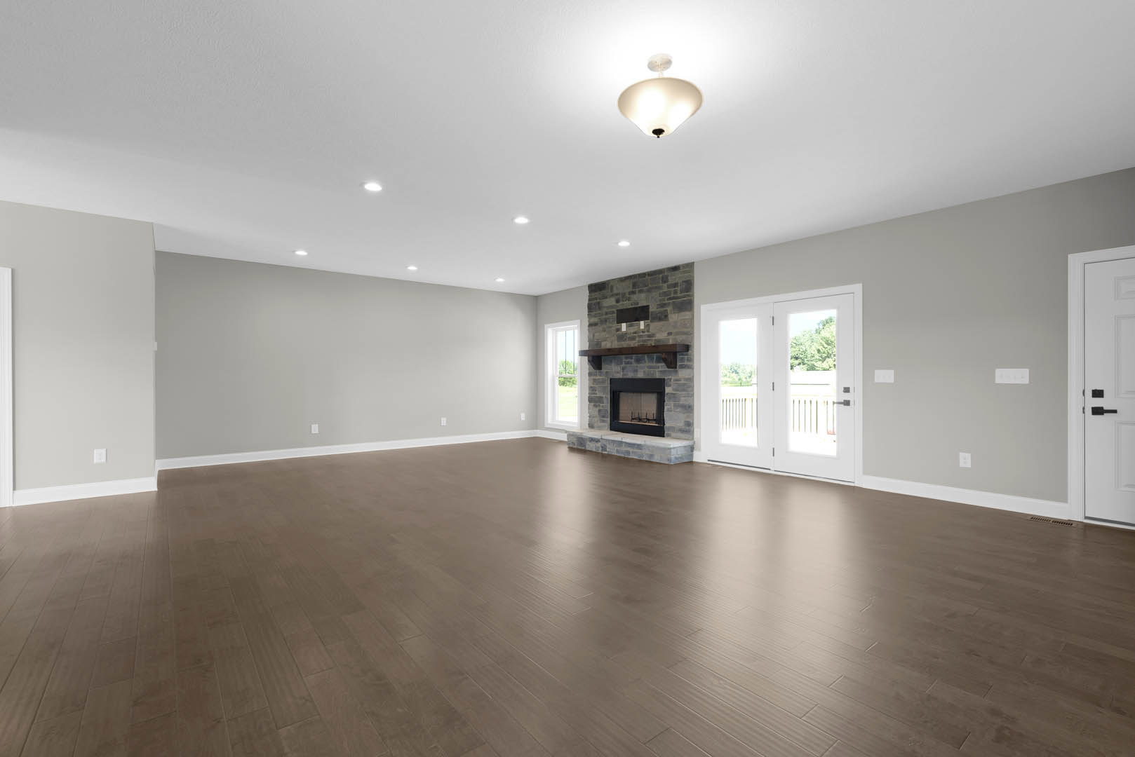 Hardwood floor living room featuring a central fireplace with glass door, white double doors with glass panels, black handle, and ceiling light fixture.