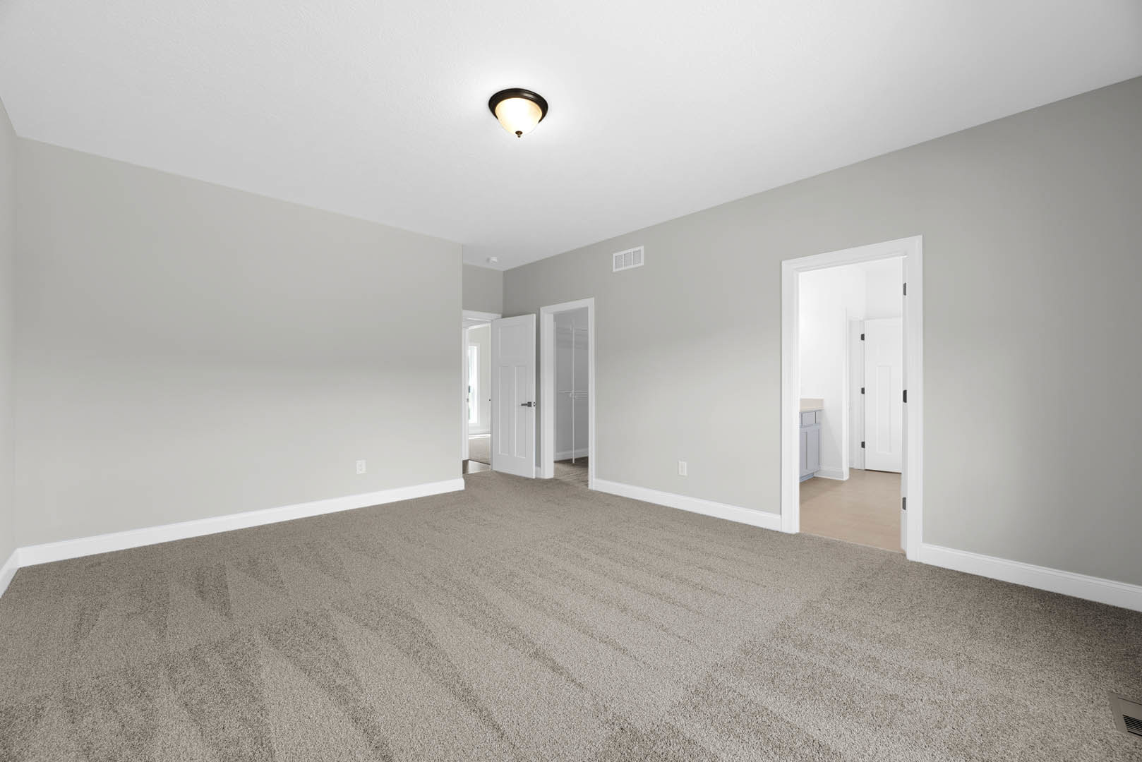 Carpeted room with white walls, ceiling-mounted light fixture, white door featuring a black handle