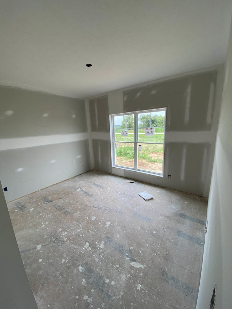 Bright room featuring a large window set in a smooth white plaster wall, natural daylight illuminating light grey flooring.