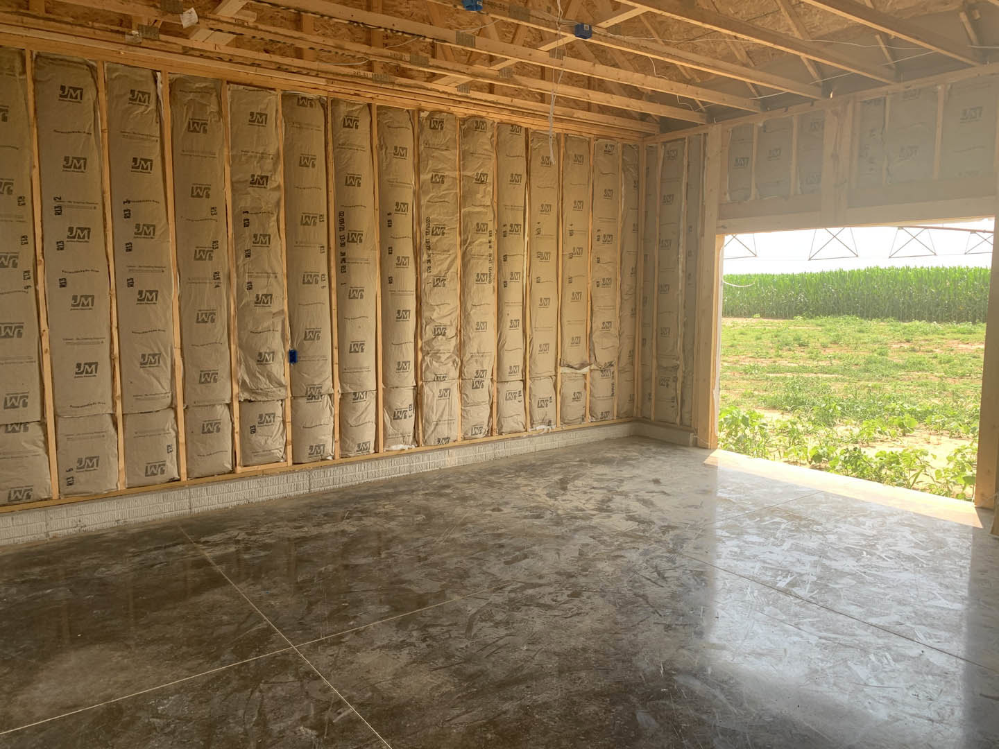 Room featuring a wall covered in brown paper bags, concrete and tile flooring, large windows overlooking a green grassy field