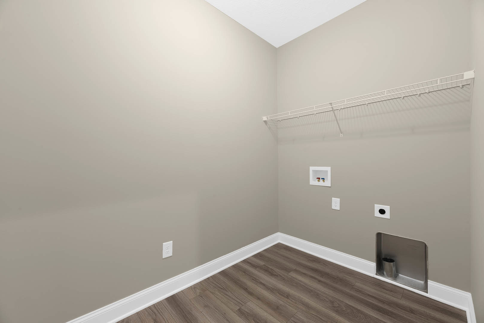 White-painted wall with a metal electrical outlet, wood flooring with white baseboard, white closet rack featuring a long metal bar, and a white box with a circular opening.