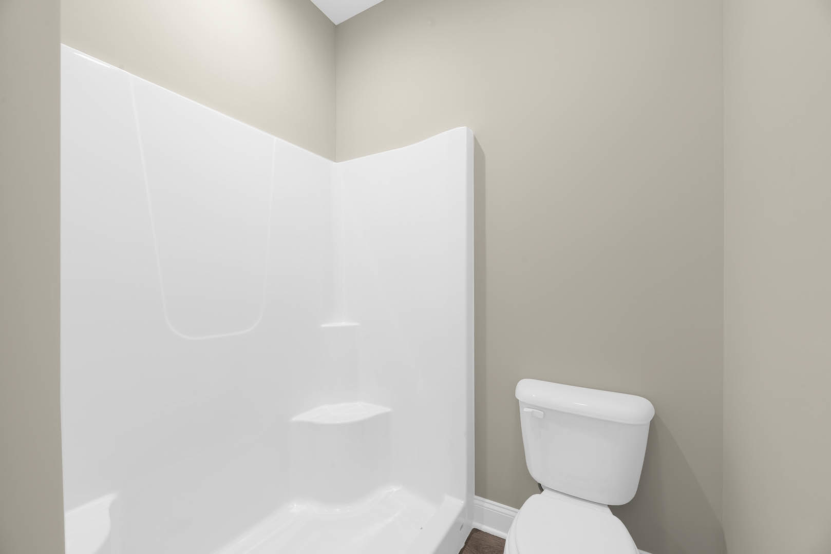 Modern bathroom with white tile walls, built-in shower with step, white toilet, and chrome bathroom accessories
