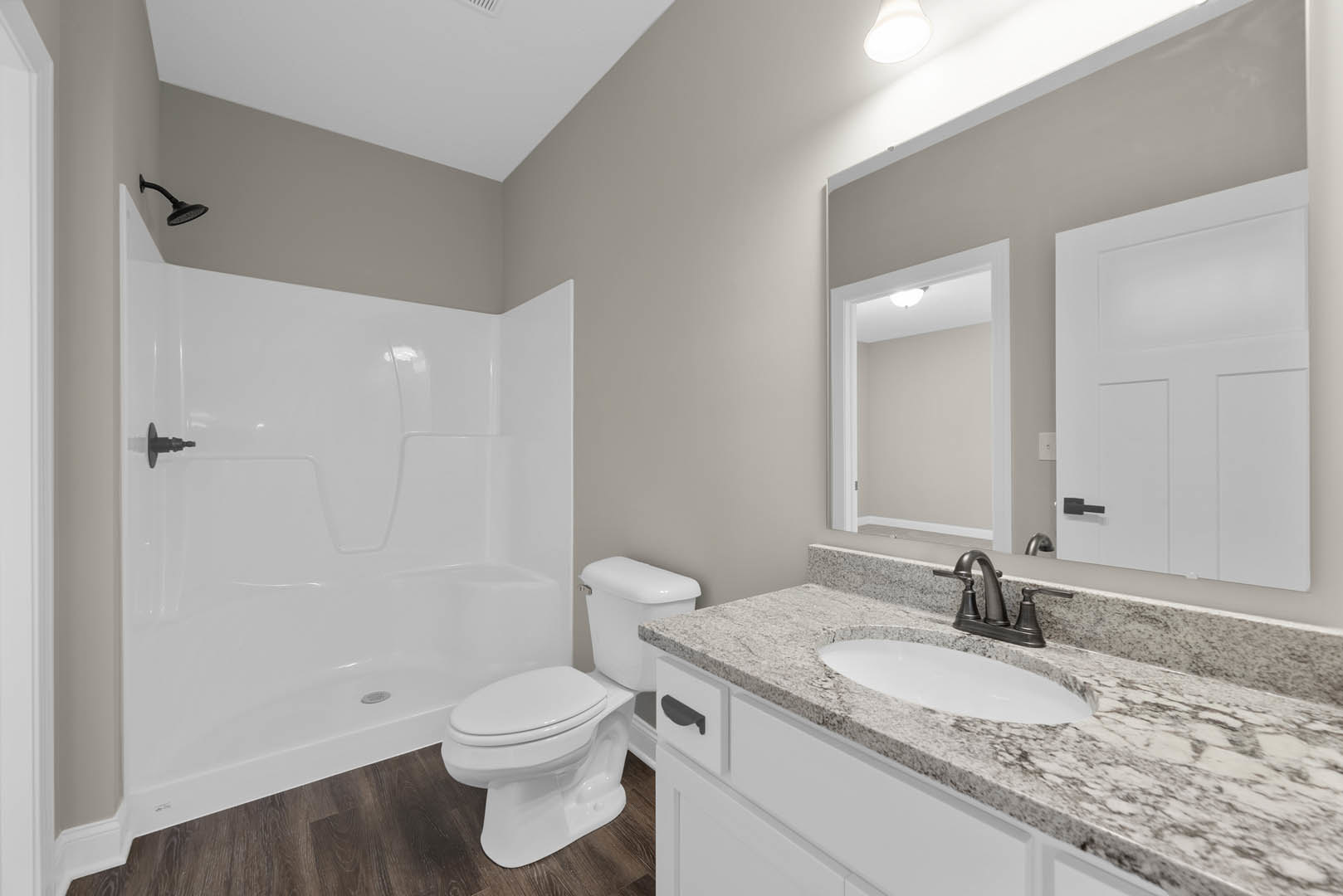 White tile bathroom featuring a glass-enclosed shower, modern white toilet, rectangular sink with chrome faucet, and black hardware on a white door