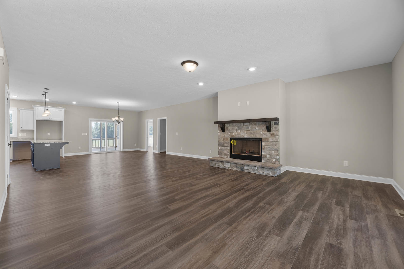 Spacious living room with hardwood floors, white plaster walls, ceiling light fixture, fireplace featuring a yellow post-it note, and a yellow flag displayed in a glass case